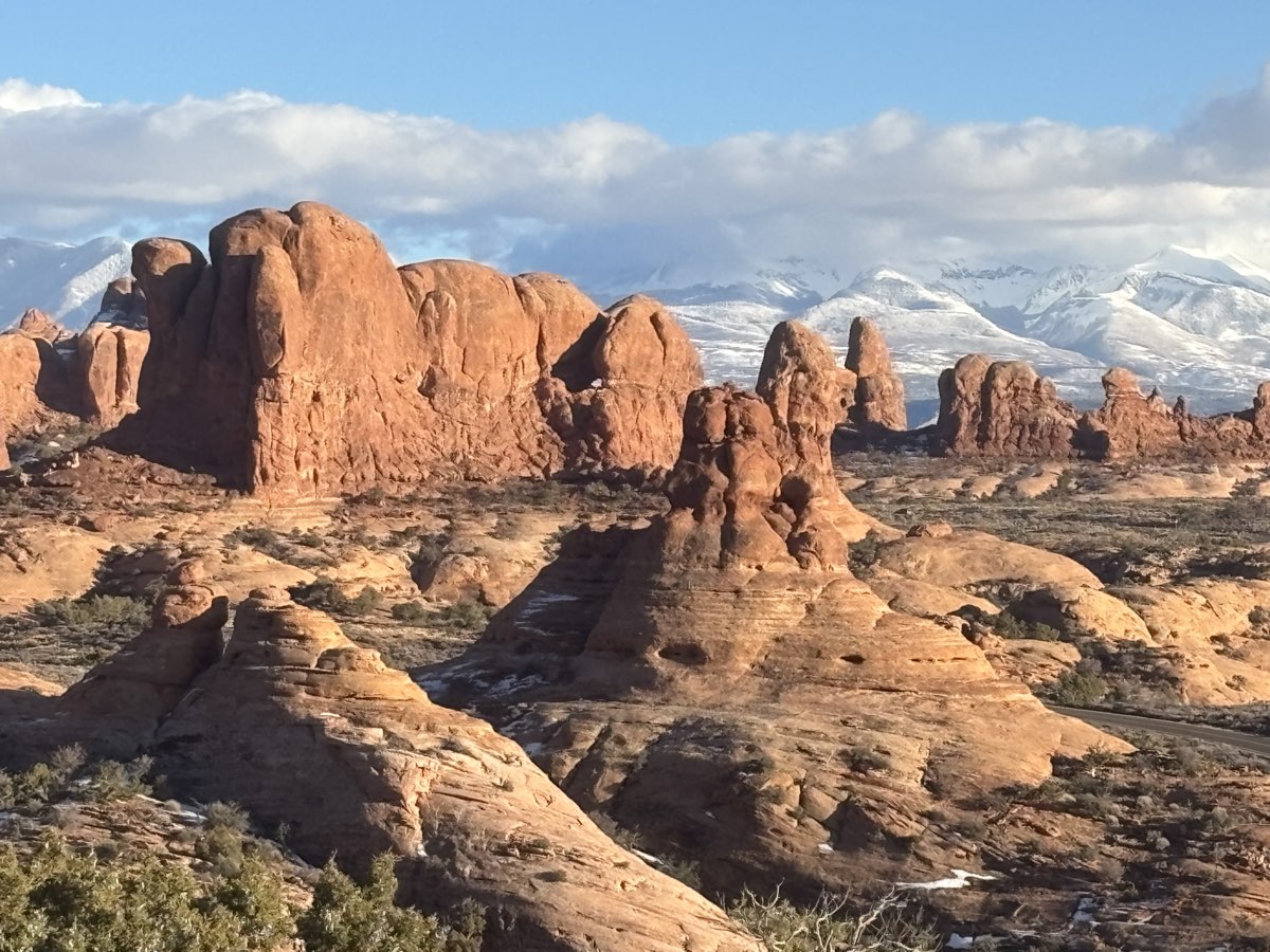 Ancient red rock formations at Arches National Park with snow-capped mountains beyond
